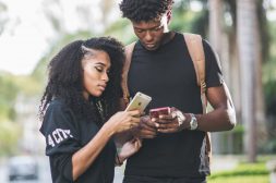 A man and a woman looking standing close together and looking at their phones