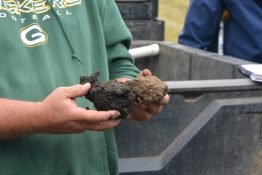 A person holds soil from a regenerative farm (blacker soil on the left) for comparison with soil from neighboring, conventional farm (right).